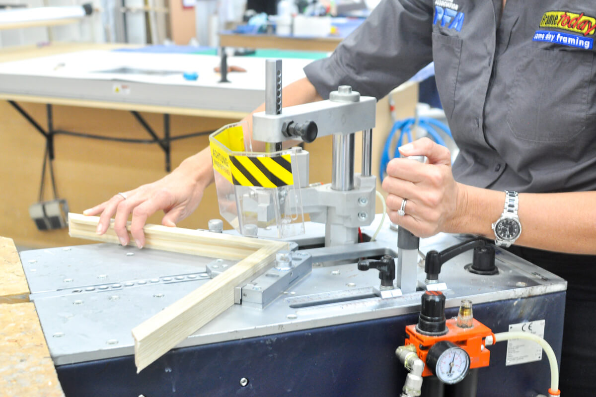 Frame today framer at work A Frame Today framing consultant joining a custom picture frame in-store